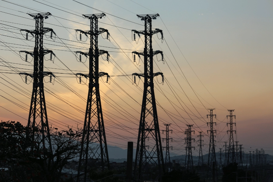 silhouette of electric towers during orange and yellow sunset